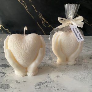 Recznie robiona swieca sojowa w ksztalcie serca, otulona delikatnymi dłonmi, wykonana z wosku sojowego w eleganckim bialym kolorze. Idealna na prezent lub jako ozdoba do wnetrz - AtmosHome.pl