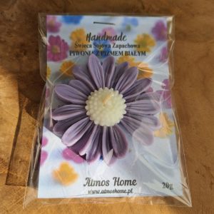 Ręcznie robiona, żółta świeca sojowa w kształcie fioletowej stokrotki, zapakowana w przezroczystą folię z etykietą "Handmade Świeca Sojowa Zapachowa - Piwonia z Pizmem Białym" marki Atmos Home.