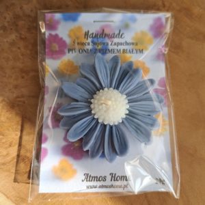 Ręcznie robiona świeca sojowa zapachowa w kształcie niebieskiej stokrotki, o zapachu piwonii z piżmem białym, zapakowana na prezent. Produkt AtmosHome.pl.