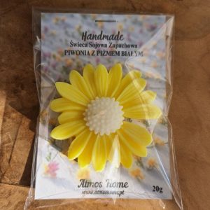 Ręcznie robiona, żółta świeca sojowa w kształcie żółtej stokrotki, zapakowana w przezroczystą folię z etykietą "Handmade Świeca Sojowa Zapachowa - Piwonia z Pizmem Białym" marki Atmos Home.