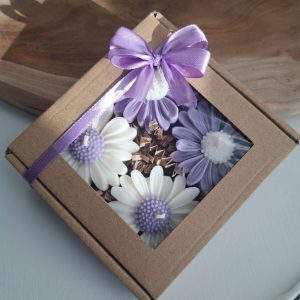 Pudełko prezentowe z okienkiem, ozdobione fioletową wstążką, zawierające świece sojowe zapachowe w kształcie stokrotek w odcieniach bieli i fioletu – idealne na podziękowania dla gości - AtmosHome.pl