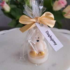Ręcznie robiona świeczka sojowa w kształcie białego misia, zapakowana w przezroczysty woreczek z zawiązaną złotą kokardką. Do woreczka przymocowana jest biała karteczka z napisem "Dziękujemy" - AtmosHome.pl